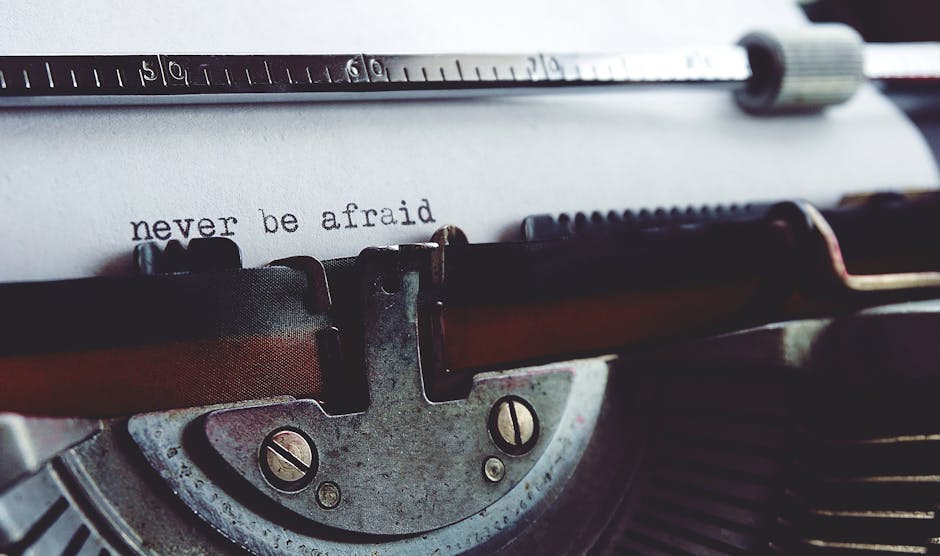 Close-up image of a vintage typewriter with a typewritten note reading 'never be afraid' visible on the paper. The typewriter features metal and plastic components, with a metal carriage and black and brown keys. The scene is well-lit, highlighting the textured surface of the typewriter and the clear, black ink characters on the white paper. This type of equipment could be associated with documentation or preparation stages during a house removal or moving process, as part of thoughtful packing or note-taking by Man with Van Old Malden, a professional removal service provider. The focus on the typewriter and the message conveys themes of reassurance and careful planning in home relocation, fitting naturally within content about furniture transport, packing, and moving logistics related to the 'Confusing Quotes? Understanding Hidden Fees in Old Malden' page.